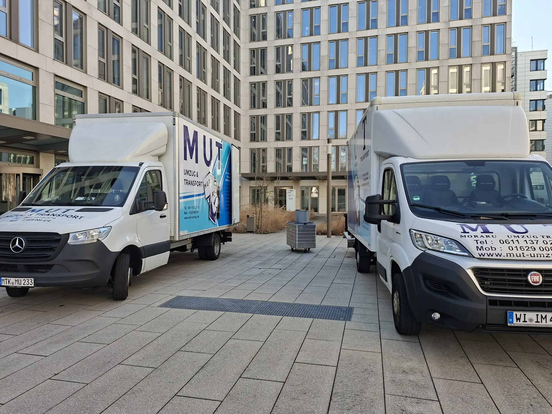 MUT-Umzugswagen und Transporter vor einem modernen Bürogebäude