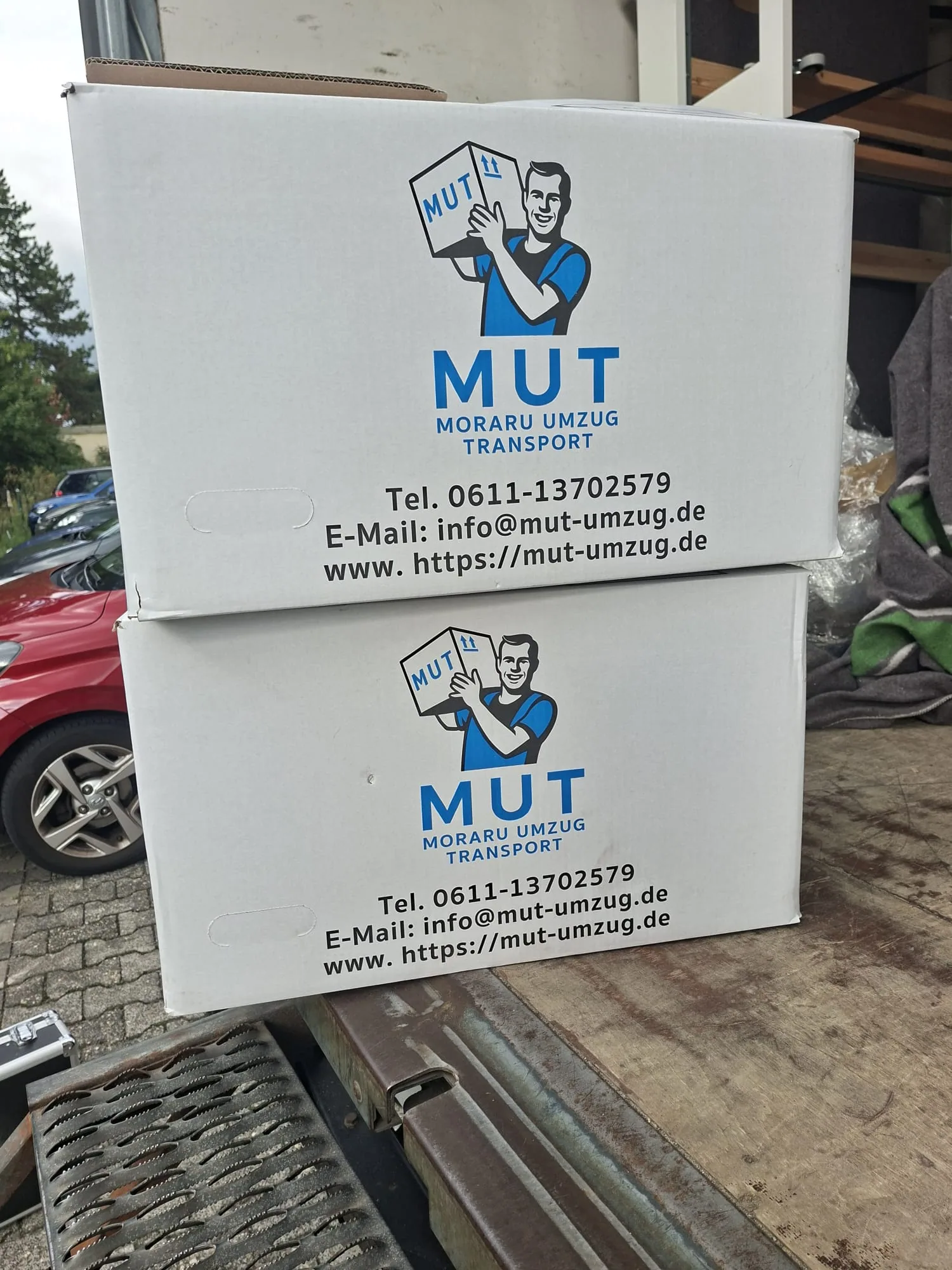 Zwei gestapelte MUT-Umzugskartons mit Firmenlogo und Kontaktdaten
